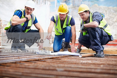 Construction workers and engineer reviewing blueprints at construction site