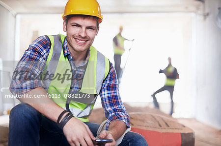 Portrait smiling construction worker with cell phone at construction site