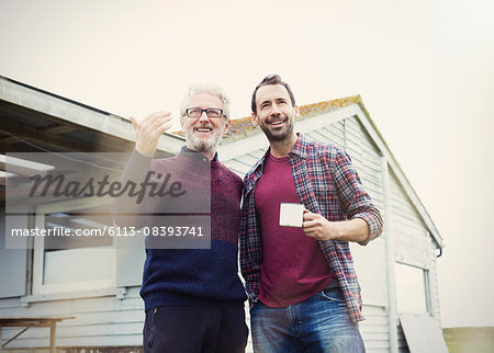 Father and son talking and drinking coffee outside house