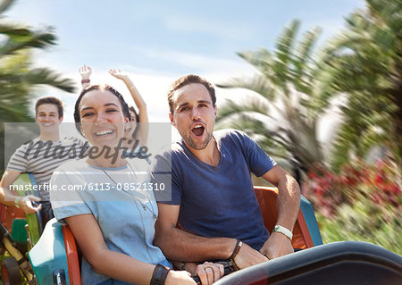 Young couple cheering on amusement park ride