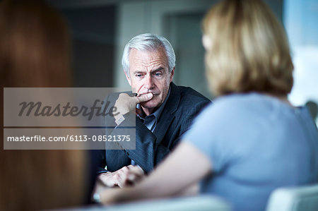 Serious senior businessman looking down in meeting