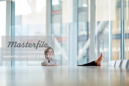 Portrait confident businesswoman with bare feet up on conference room table