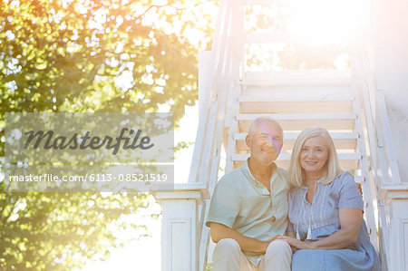 Portrait smiling senior couple sitting on summer stairs