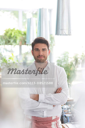 Portrait confident waiter with arms crossed in cafe