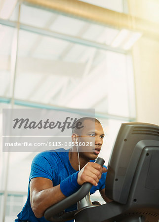 Determined man on elliptical trainer at gym