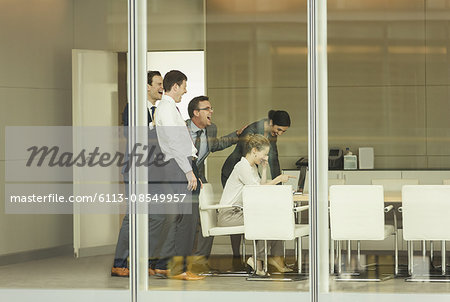 Business people laughing at laptop in conference room