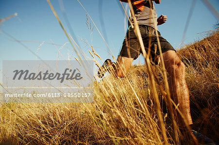 Man running through tall grass on sunny trail