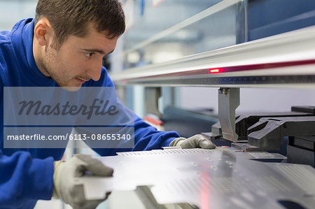 Worker operating laser cutter in steel factory