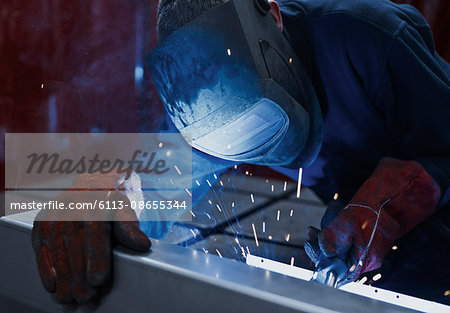 Welder using welding torch in steel factory