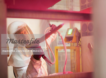 Worker painting steel red in steel factory