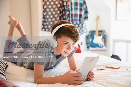 Boy with headphones listening to music on digital tablet