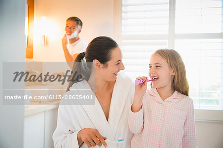 Mother and daughter brushing teeth in bathroom