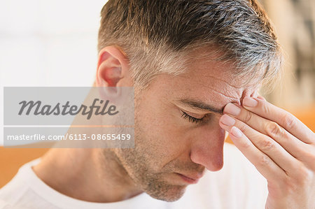 Close up of man with headache touching forehead