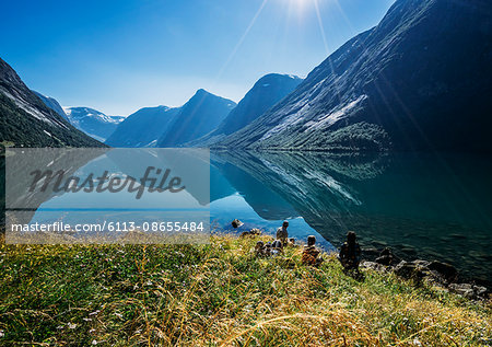 Friends relaxing at sunny tranquil mountain lakeside, Norway