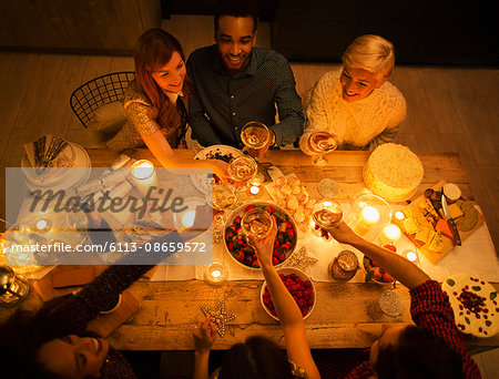 Overhead view friends toasting champagne glasses at candlelight Christmas dessert Overhead view friends toasting champagne glasses at candlelight Christmas dessert