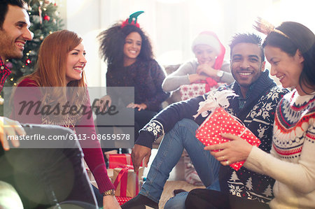 Friends opening Christmas gifts in living room