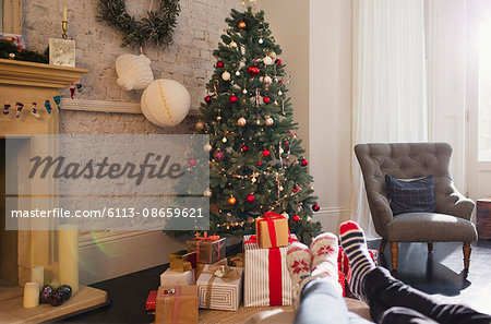 Relaxed couple wearing socks with feet up near Christmas tree in living room