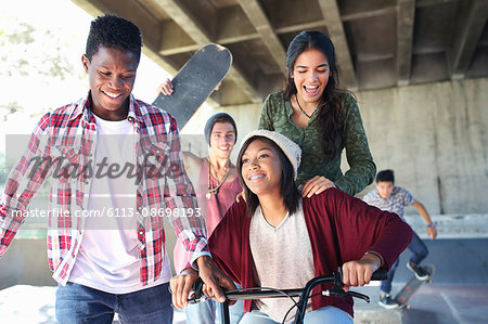 Teenage friends with skateboards and BMX bicycle at skate park