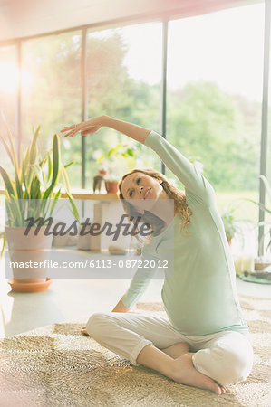 Pregnant woman practicing yoga doing side stretch