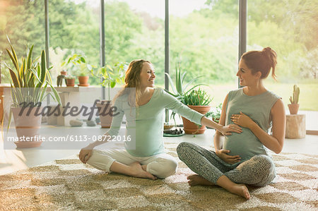 Pregnant women touching stomach in yoga class