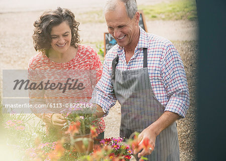 Plant nursery worker helping woman with flowers