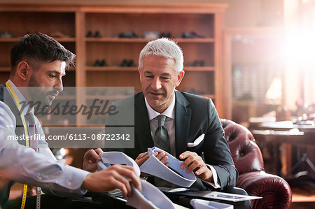 Tailor and businessman browsing shirt collars in menswear shop Tailor and businessman browsing shirt collars in menswear shop