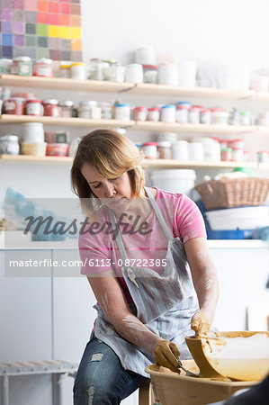 Mature woman using pottery wheel in studio