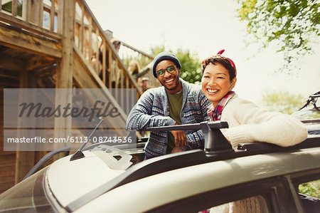 Portrait smiling couple standing in car sunroof outside cabin