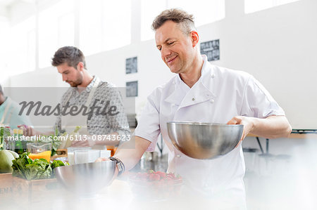 Chef teacher holding bowls in cooking class kitchen