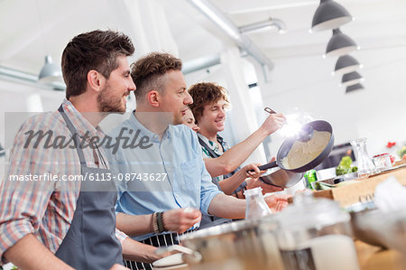 Male students enjoying cooking class in kitchen