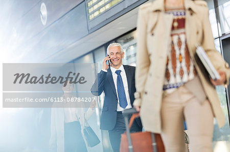 Businessman talking on cell phone walking in airport concourse