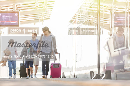 Family walking pulling suitcases in airport concourse