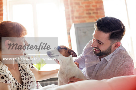 Couple petting Jack Russell Terrier dog on bed