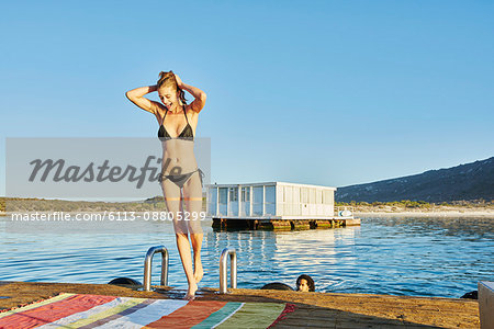 Young woman in bathing suit on sunny summer dock