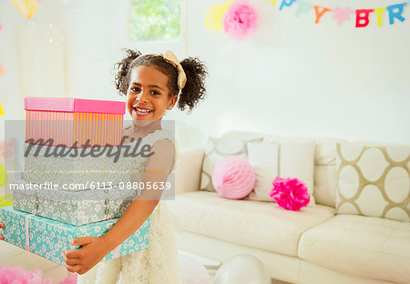 Portrait smiling girl carrying stack of birthday gifts