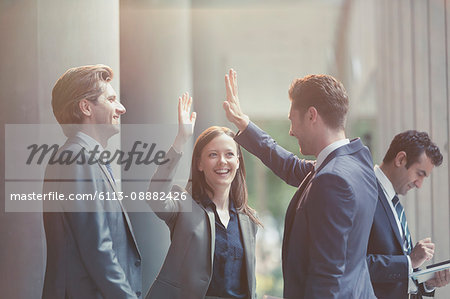 Business people high-fiving in office lobby