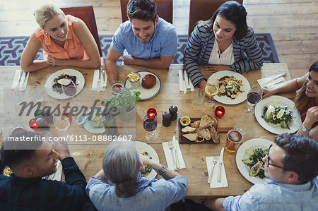 Overhead view friends talking and dining at restaurant table