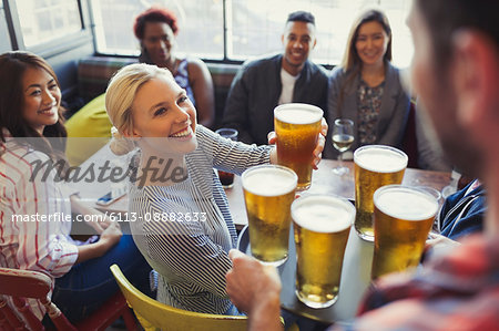 Bartender serving beers on tray to friends in bar