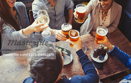 Overhead view friends celebrating, toasting beer and wine glasses at table in bar Overhead view friends celebrating, toasting beer and wine glasses at table in bar
