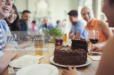 Woman serving chocolate birthday cake to friends at restaurant table Woman serving chocolate birthday cake to friends at restaurant table
