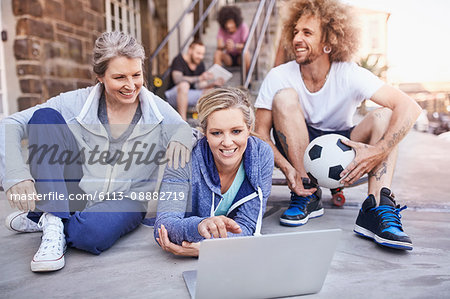 Friends with soccer ball hanging out using laptop