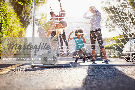 Friends playing soccer on sunny urban summer street