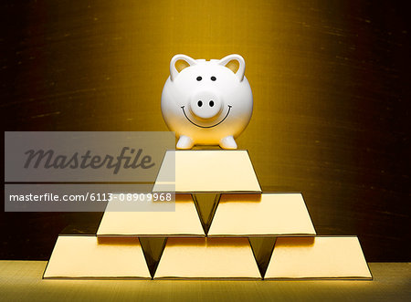Smiling piggy bank on top of stacked gold bars Smiling piggy bank on top of stacked gold bars