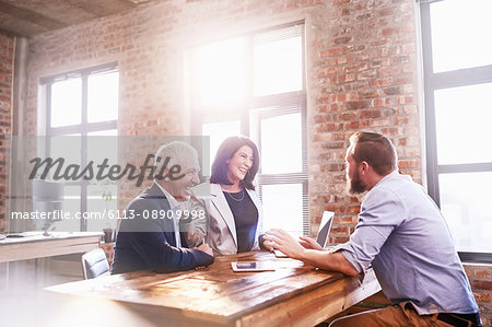 Smiling business people meeting at table in office Smiling business people meeting at table in office