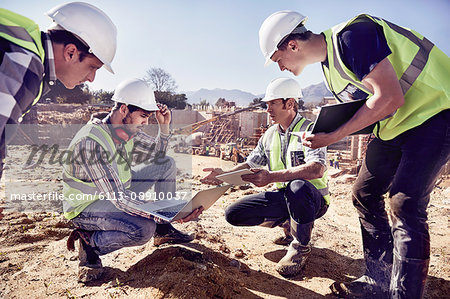 Construction workers and engineers using digital tablets at sunny construction site