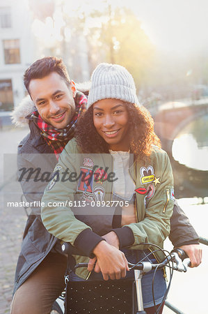 Portrait young couple with bicycle hugging along sunny canal