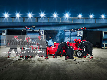 Pit crew working on formula one race car in pit stop
