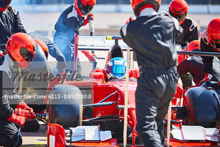 Pit crew working on formula one race car in pit lane