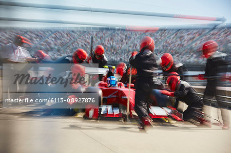 Pit crew replacing tires on formula one race car in pit lane