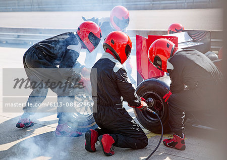 Pit crew replacing tires on formula one race car in pit lane